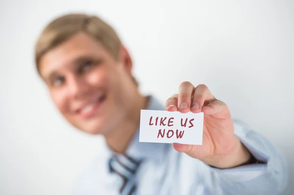 Handsome businessman showing "like us now" text on a business card — Stock Photo, Image
