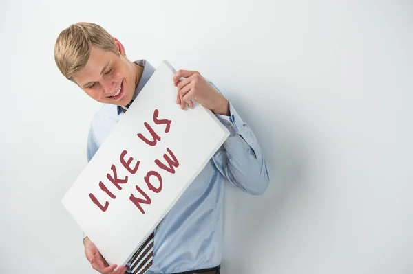 Handsome businessman showing "like us now" text on a billboard — Stock Photo, Image