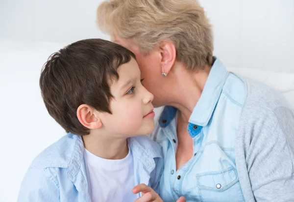 Grandmother with grandson having fun at home - whispering secret — Stock Photo, Image