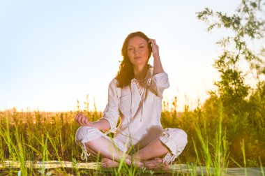 Yeşil çimlerde yoga yapan kadın.