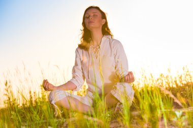 Yeşil çimlerde yoga yapan kadın.