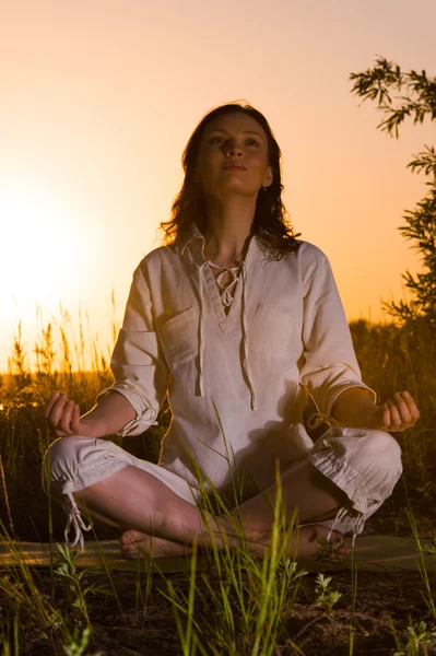 Schöne Yoga-Frau sitzt gegen Sonnenaufgang — Stockfoto