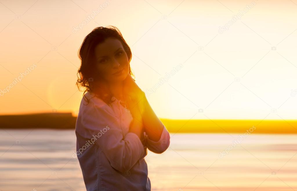 Young woman walking on beach under sunset light