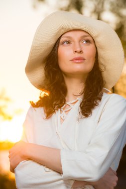 Hasır şapka gülen ve having fun karşı günbatımı giyen kadın bir