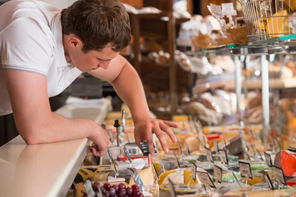 Negozio che lavora in una cassa di vetro di formaggio in un negozio di alimentari — Foto Stock