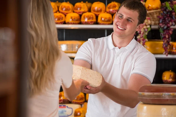 Male salesman in cheese store with a female customer — Stock Photo, Image