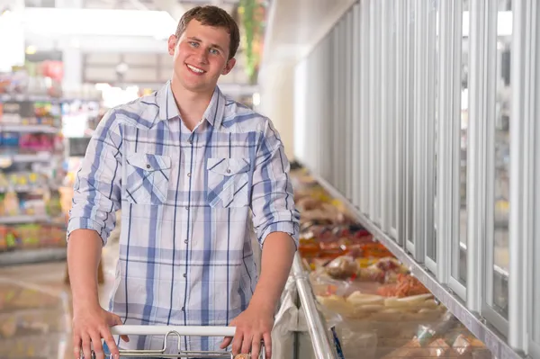 Jonge man winkelen voor bevroren voedsel in een supermarkt — Stockfoto