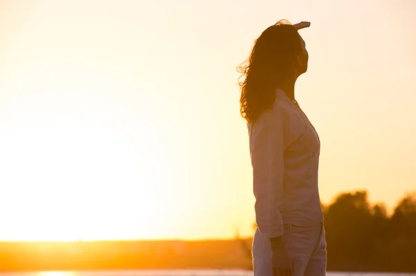 Mujer joven y hermosa en la luz del atardecer mirando lejos. Fotógrafo —  Fotos de Stock