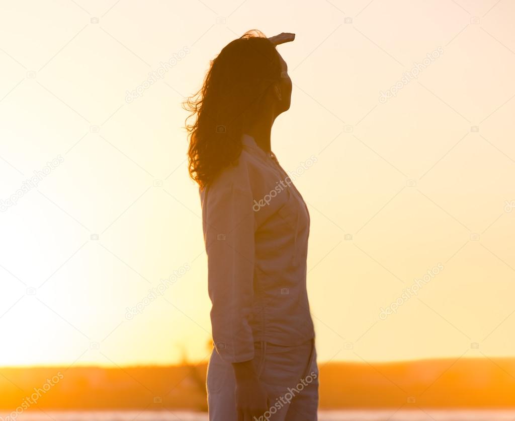 Young and beautiful woman in sunset light looking far away. Phot