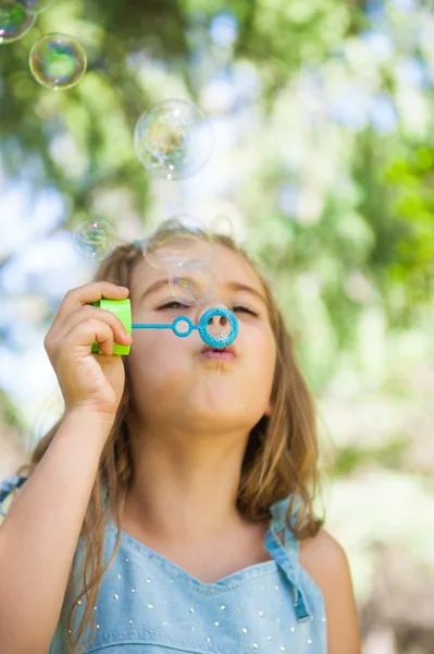 Kleines Mädchen pustet Seifenblasen — Stockfoto