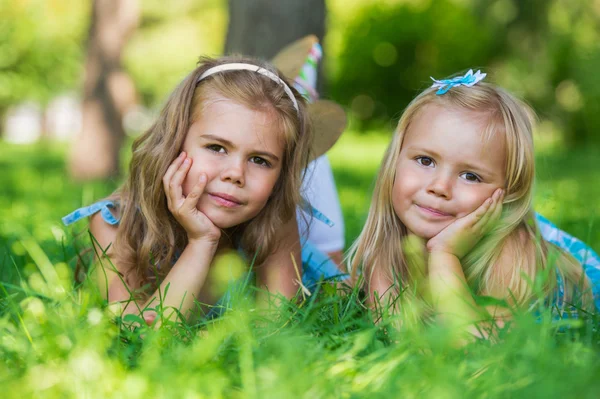 Twee kleine leuke meisjes op grasveld in het park — Stockfoto