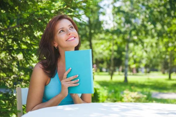 Mujer adulta positiva leyendo libro al aire libre — Foto de Stock