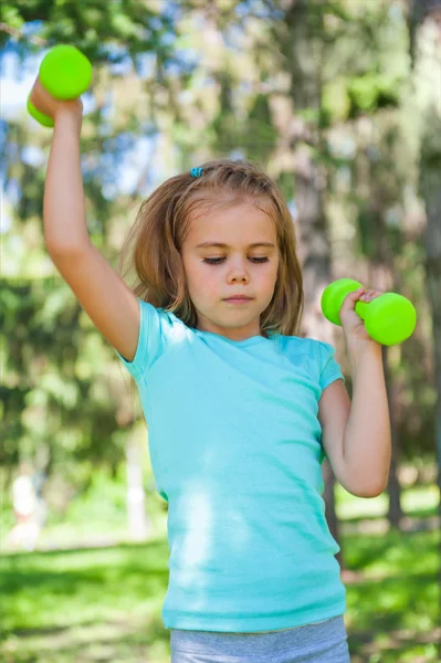 快乐的小女孩在户外公园举哑铃 — 图库照片