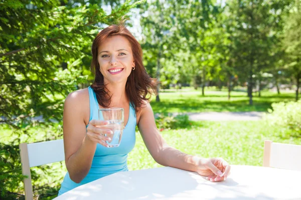 Retrato de una joven hermosa mujer bebiendo agua en el picnic — Foto de Stock