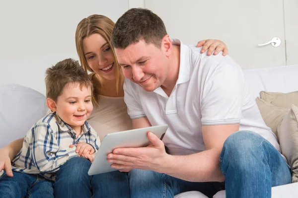 Счастливая семья дома с помощью электронного планшета — стоковое фото