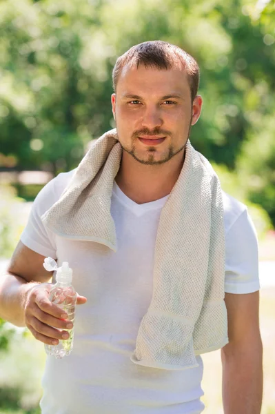 Joven atleta masculino sexy se está refrescando con agua — Foto de Stock