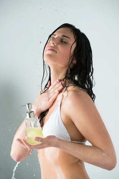Mooi meisje douchen. bedrijf glazen fles met douchegel — Stockfoto