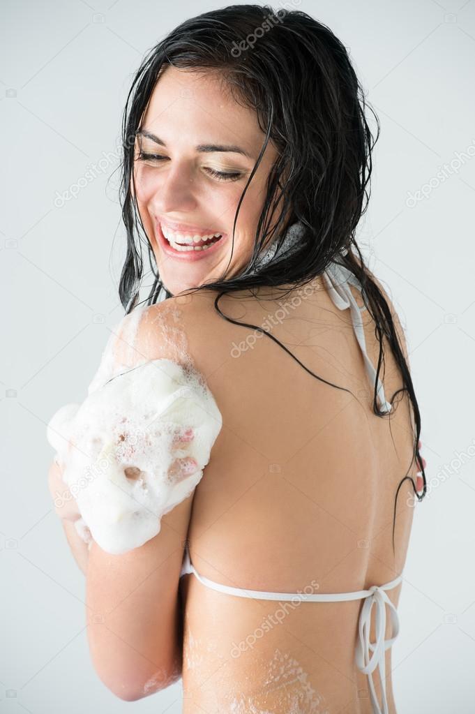 Young woman washing body with shower gel