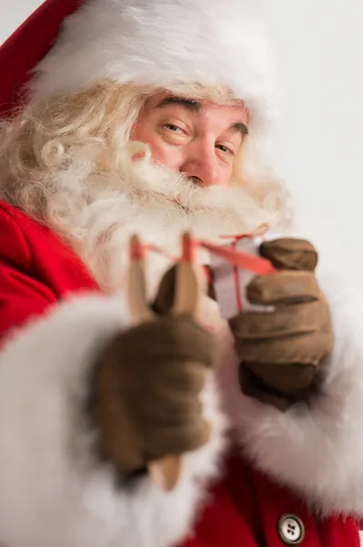 Porträt eines glücklichen Weihnachtsmannes, der mit Schleuder auf ein Weihnachtsgeschenk zielt — Stockfoto