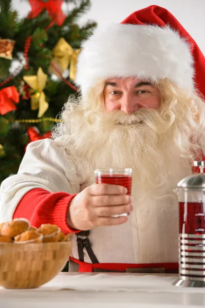 Portret szczęśliwy santa Claus w domu jedzenie ciasteczek i drinkin — Zdjęcie stockowe