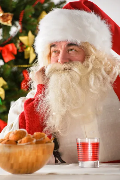 Portret szczęśliwy santa Claus w domu jedzenie ciasteczek i drinkin — Zdjęcie stockowe