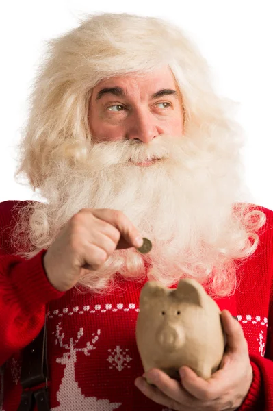 Authentic Santa Claus holding piggy bank and putting golden coin — Stock Photo, Image