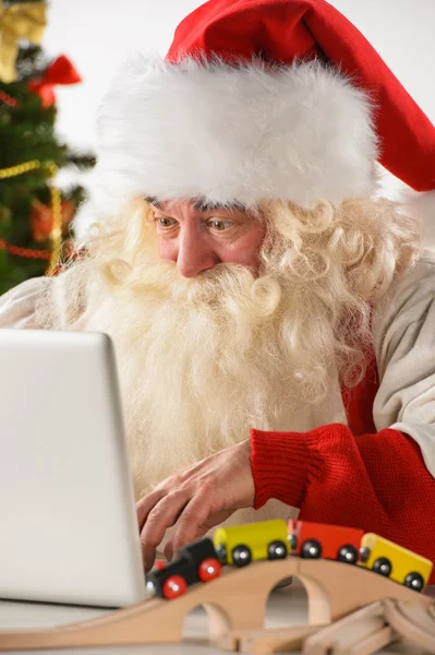 Real Santa Claus trabajando en el ordenador portátil con la cara sorprendida en casa —  Fotos de Stock