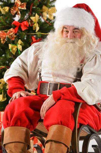 サンタ クロース クリスマスの木の近くのロッキングチェアに座っています。 — ストック写真