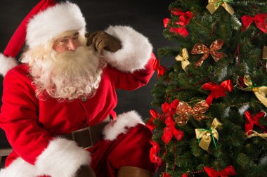 Noel Baba duran karanlık odada Noel ağacının yakınında