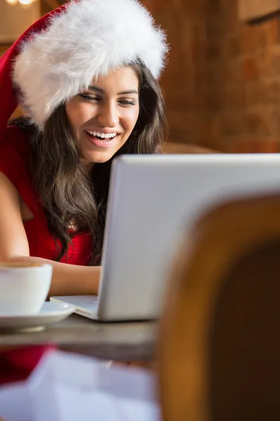 Vacker ung kvinna jultomten röd hatt sitter på café — Stockfoto