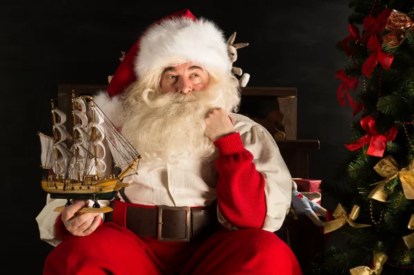 Weihnachtsmann zu Hause spielt mit neuem Spielzeug am Weihnachtsbaum — Stockfoto