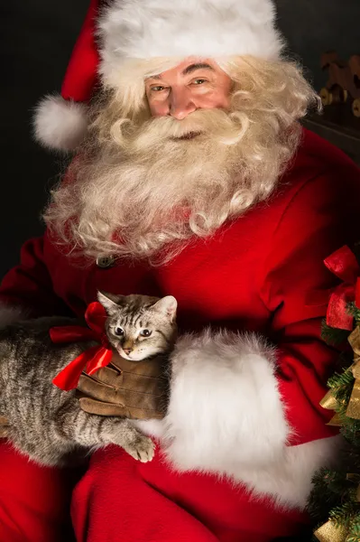 Santa Claus making a most wanted gift to a child placing cute ca — Stock Photo, Image