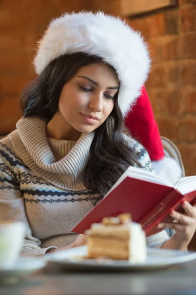 Hermosa mujer joven con Santa Claus sombrero rojo sentado en la cafetería — Foto de Stock