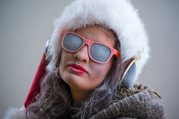 Donna con cappello e occhiali da sole di Babbo Natale ascoltando musica — Foto Stock