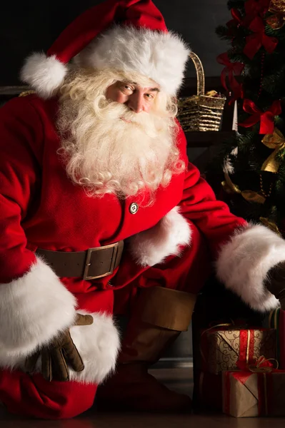 Santa att placera presenter under granen i mörkt rum — Stockfoto