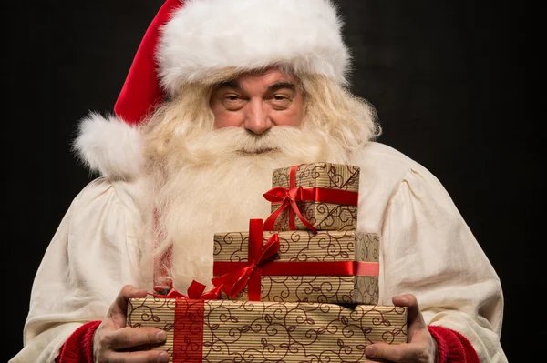 Weihnachtsmann trägt großen Stapel Weihnachtsgeschenke — Stockfoto
