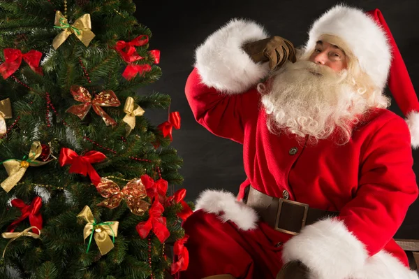 Papai Noel de pé perto da árvore de Natal no quarto escuro — Fotografia de Stock