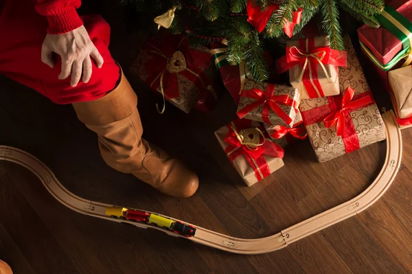 Weihnachtsmann beim Spielen mit hölzerner Eisenbahn in der Nähe — Stockfoto