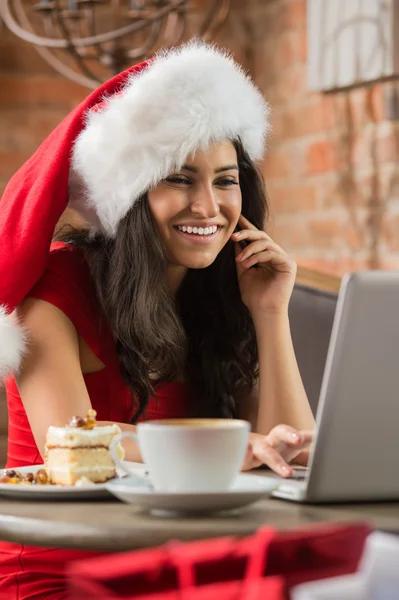 Vacker ung kvinna jultomten röd hatt sitter på café — Stockfoto