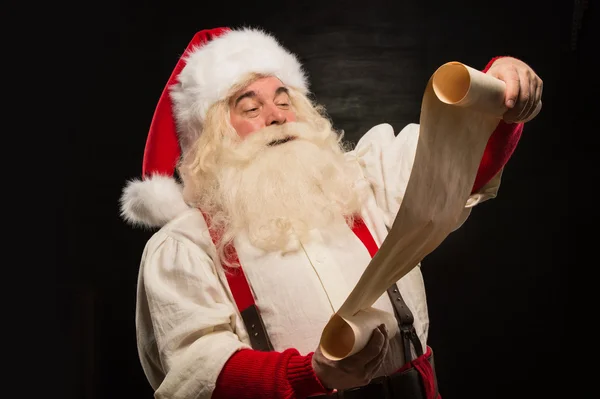 Portrait of happy Santa Claus reading Christmas letter — Stock Photo, Image
