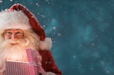 Santa Claus opening gift box outdoors at North Pole