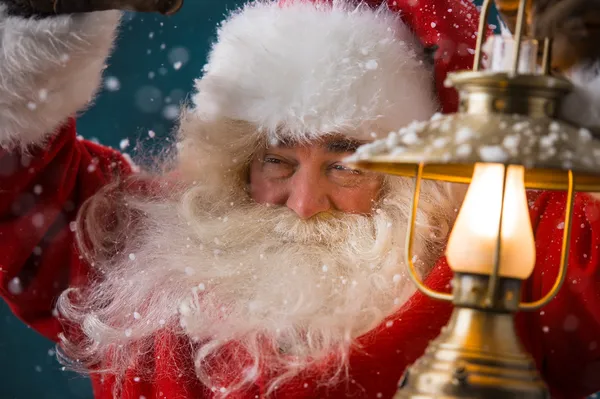 Santa Claus sostiene una linterna brillante mientras se escabulle a su casa —  Fotos de Stock