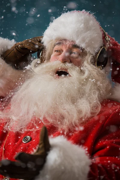 Santa Claus is listening to music in headphones outdoors at North pole — Stock Photo, Image