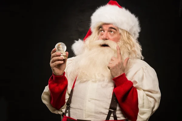 Weihnachtsmann hält Schneekugel in der Hand — Stockfoto