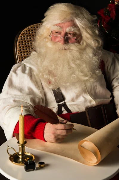 Santa claus sedí doma a zápis do seznamu — Stock fotografie