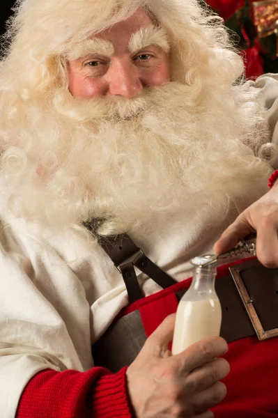 Santa Claus opening glass bottle with milk