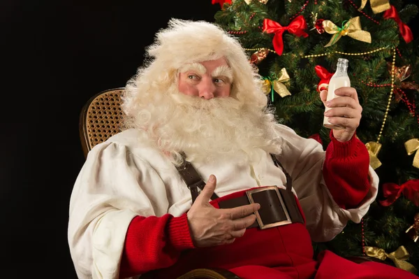 Санта-Клаус пьет молоко из стеклянной бутылки — стоковое фото