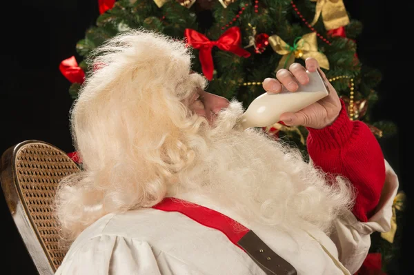 Санта-Клаус пьет молоко из стеклянной бутылки — стоковое фото
