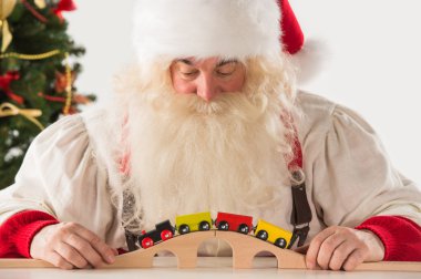 Noel Baba oturma ve demiryolu oyuncakla oynamak