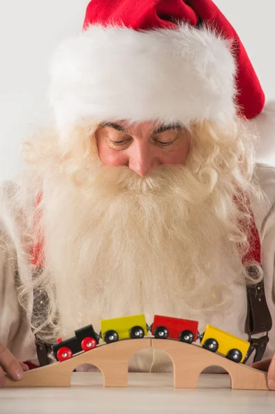 Noel Baba oturma ve demiryolu oyuncakla oynamak — Stok fotoğraf